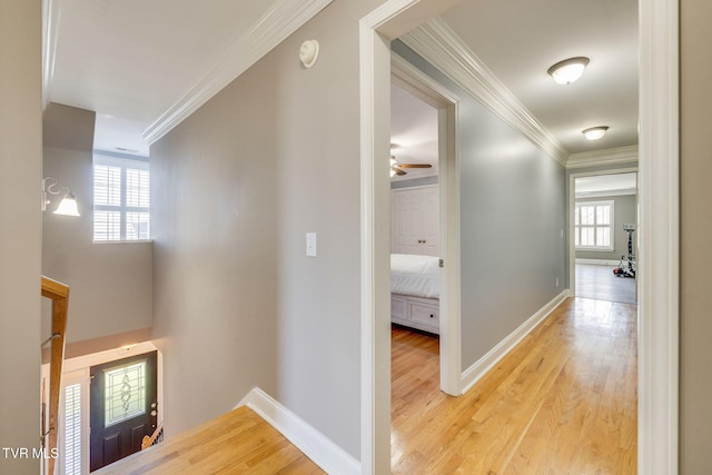 hallway featuring light wood-style flooring, baseboards, and ornamental molding