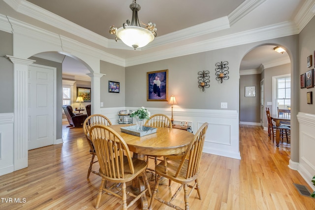 dining space with visible vents, arched walkways, decorative columns, light wood-style floors, and wainscoting