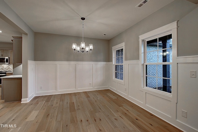 2442 Haystack Cir, Piney Flats, TN 37686 - unfurnished dining area with light wood-style flooring, a decorative wall, a chandelier, and wainscoting