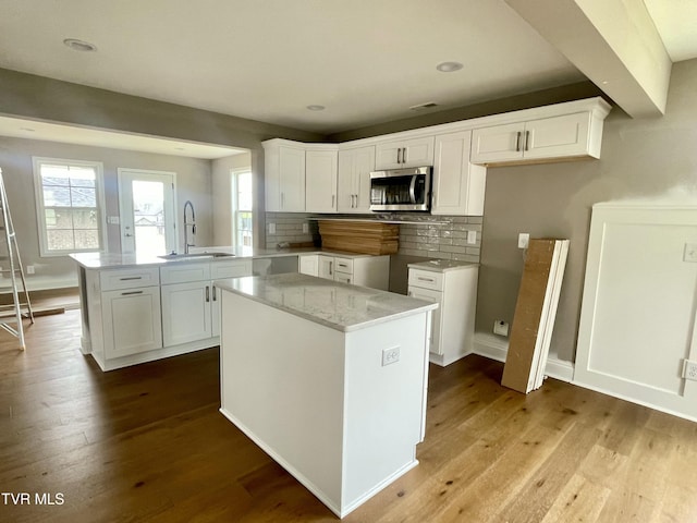 4076 Maize Pl, Piney Flats, TN 37686 - kitchen with stainless steel microwave, a sink, a peninsula, decorative backsplash, and wood finished floors