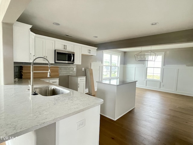 4076 Maize Pl, Piney Flats, TN 37686 - kitchen featuring stainless steel microwave, a sink, a decorative wall, dark wood-style floors, and backsplash