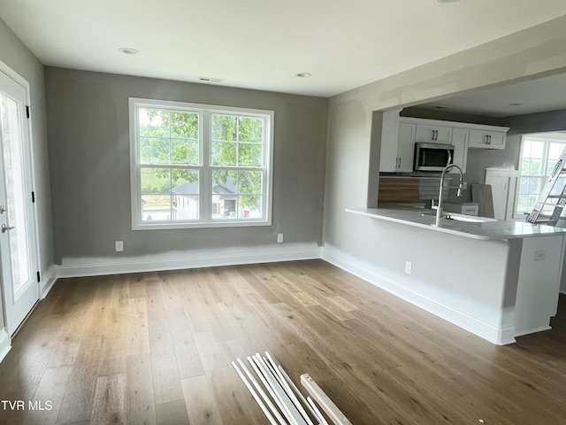4076 Maize Pl, Piney Flats, TN 37686 - kitchen with a sink, stainless steel microwave, white cabinets, wood finished floors, and a peninsula