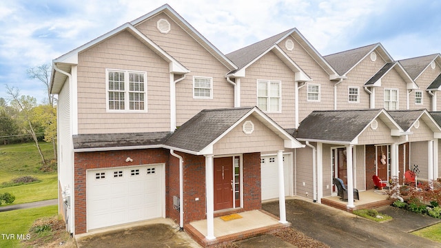 multi unit property featuring an attached garage, covered porch, aphalt driveway, and brick siding