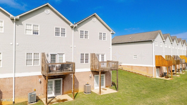 rear view of house featuring brick siding, central air condition unit, and a lawn