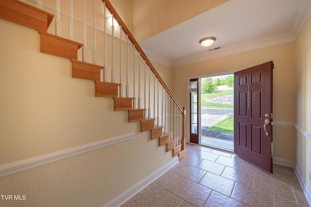 foyer entrance with crown molding, visible vents, stairway, baseboards, and stone tile flooring