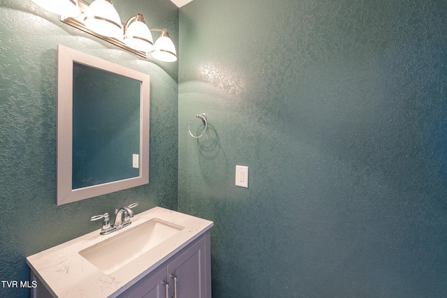 bathroom with vanity, a textured wall, and an inviting chandelier