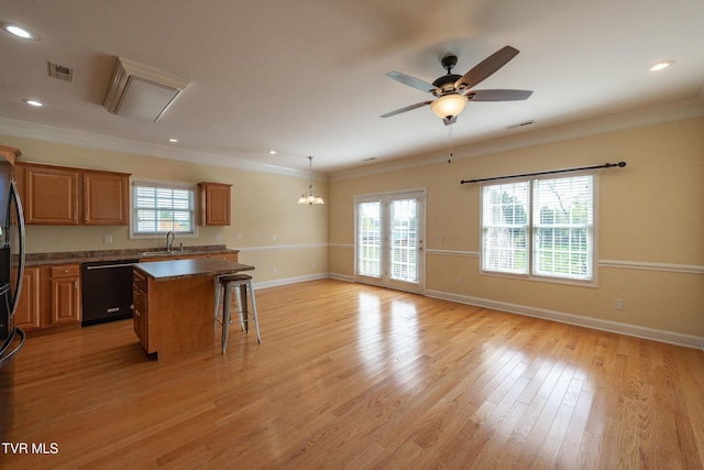 kitchen with light wood-style flooring, a center island, black dishwasher, visible vents, and a healthy amount of sunlight
