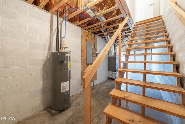 interior space featuring electric panel, water heater, concrete flooring, and concrete block wall