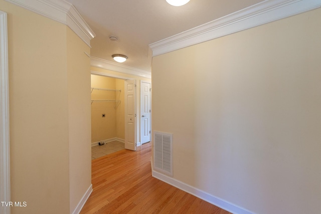 hall with light wood finished floors, visible vents, baseboards, and crown molding