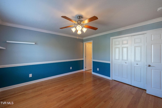 unfurnished bedroom with baseboards, a closet, ornamental molding, a ceiling fan, and wood finished floors