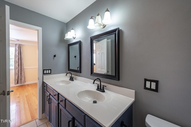 bathroom featuring a sink, toilet, double vanity, and wood finished floors
