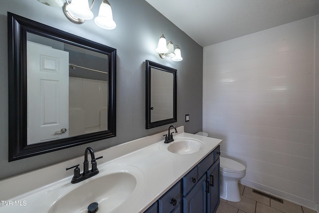 bathroom with visible vents, toilet, a sink, tile patterned floors, and double vanity