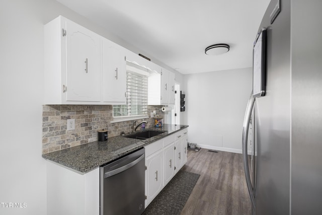 kitchen featuring appliances with stainless steel finishes, white cabinetry, backsplash, dark wood finished floors, and a sink