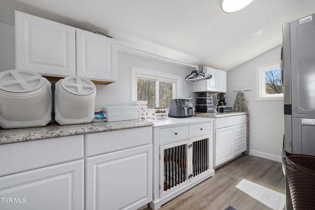 kitchen featuring lofted ceiling, white cabinetry, baseboards, and wood finished floors