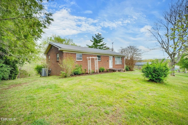 view of front of home with brick siding, a front lawn, cooling unit, and metal roof