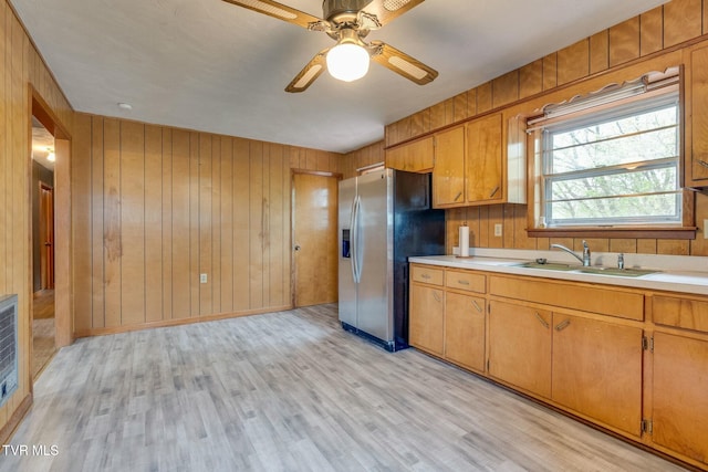 kitchen with a sink, light countertops, stainless steel fridge, and light wood-style flooring
