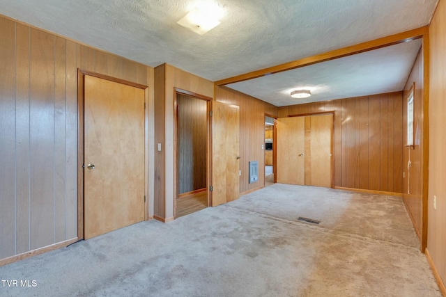 interior space featuring visible vents, wood walls, carpet floors, and a textured ceiling