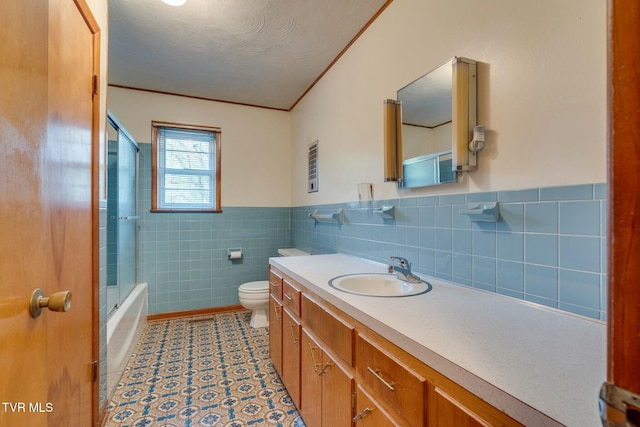 full bathroom with crown molding, vanity, toilet, wainscoting, and tile walls