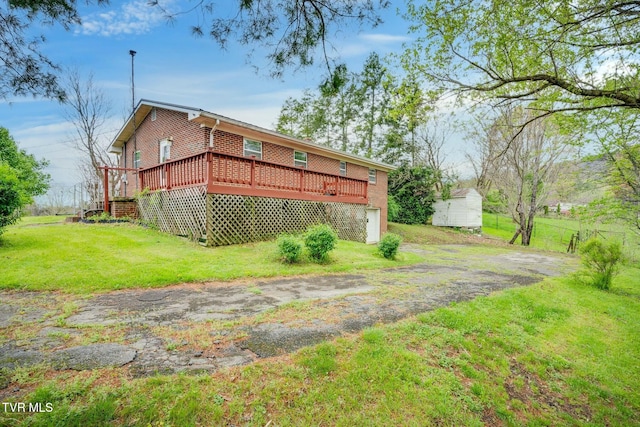 back of house with brick siding, a deck, a garage, and a lawn