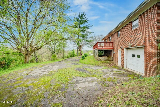 view of yard featuring an attached garage, driveway, and a deck