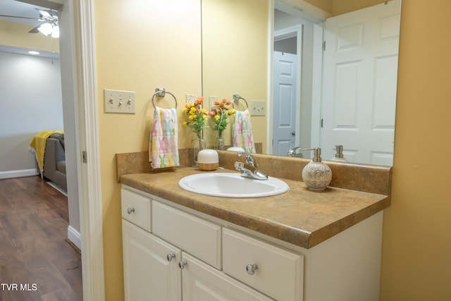 bathroom with wood finished floors, a ceiling fan, vanity, and baseboards