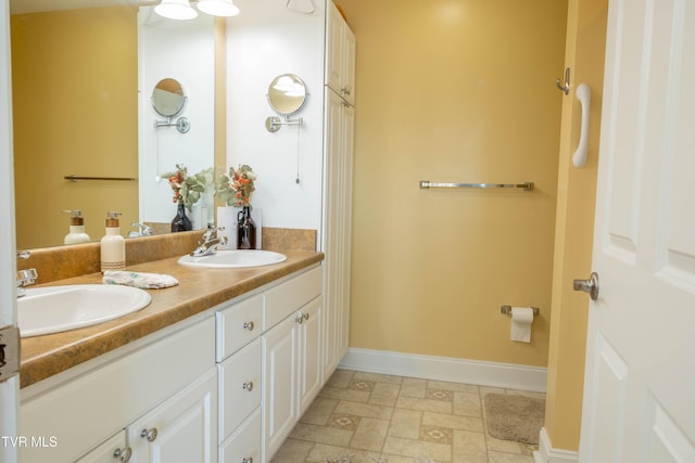 full bathroom with double vanity, baseboards, and stone finish floors