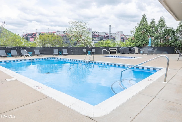 community pool featuring a hot tub, fence, and a patio area