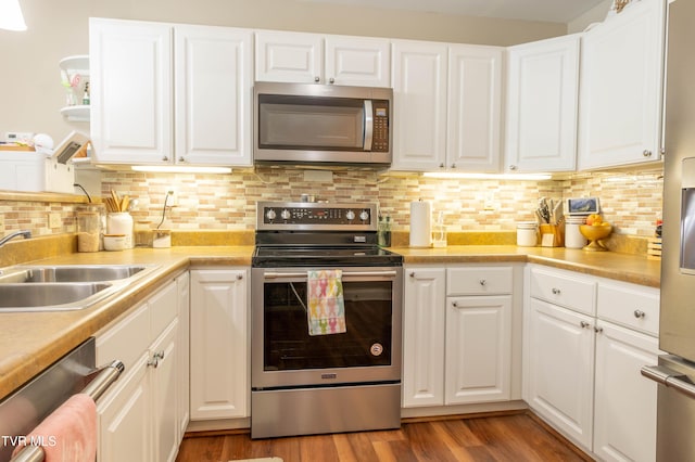 kitchen featuring stainless steel appliances, a sink, white cabinetry, light countertops, and light wood finished floors
