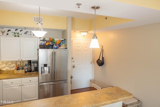 kitchen featuring high quality fridge, white cabinetry, backsplash, and hanging light fixtures