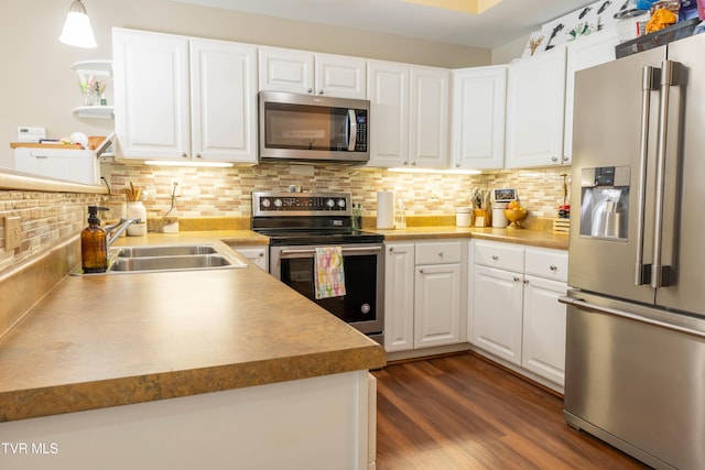 kitchen featuring stainless steel appliances, a sink, white cabinets, and tasteful backsplash