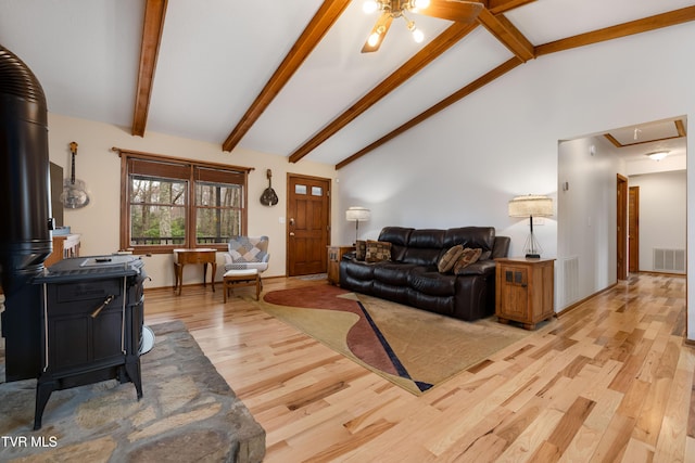 living room featuring light wood-type flooring, attic access, a wood stove, and visible vents