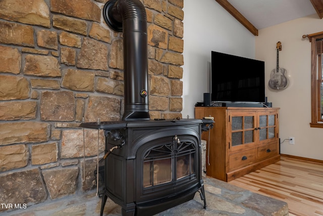 details featuring wood finished floors, a wood stove, baseboards, and beam ceiling