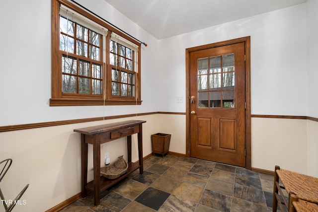 entryway featuring baseboards, stone finish flooring, and plenty of natural light