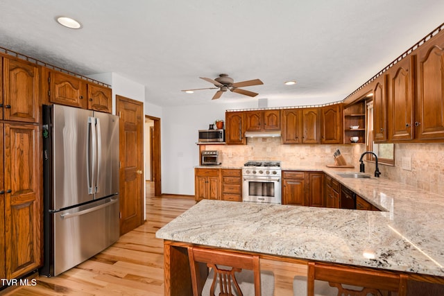 kitchen featuring a peninsula, open shelves, appliances with stainless steel finishes, a sink, and backsplash