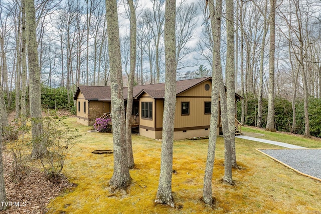view of front of home with a front yard, crawl space, and a shingled roof