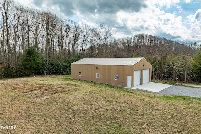 exterior space with a view of trees, a yard, a garage, and an outdoor structure
