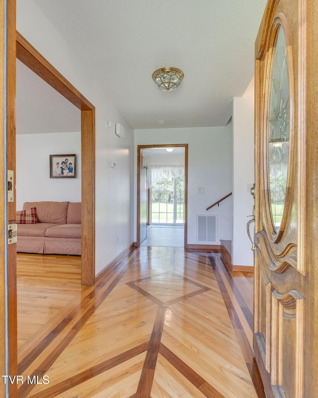 foyer entrance featuring visible vents, baseboards, and wood finished floors