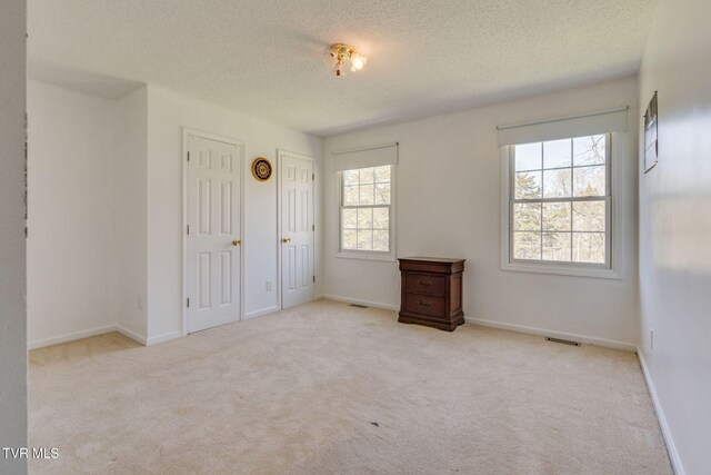 unfurnished bedroom with carpet floors, baseboards, visible vents, and a textured ceiling