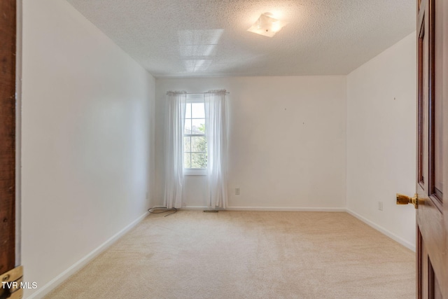 spare room with carpet floors, baseboards, and a textured ceiling