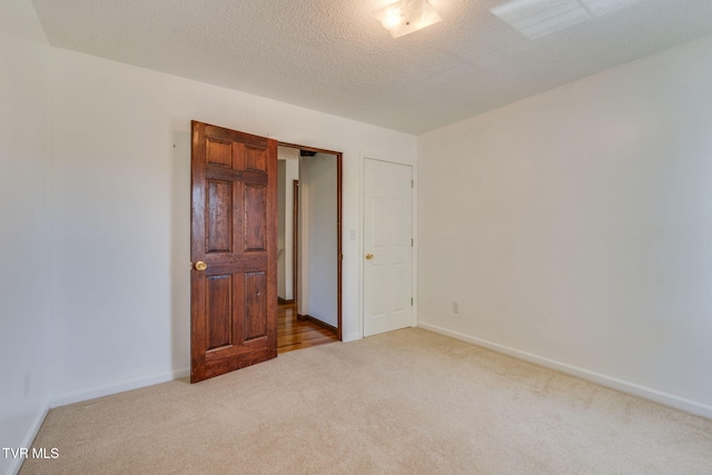 empty room with carpet, baseboards, and a textured ceiling
