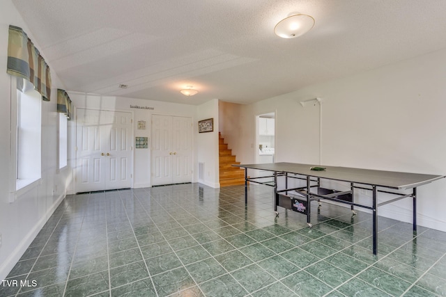 interior space with stairs, baseboards, and a textured ceiling