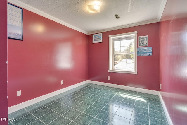 unfurnished room featuring dark tile patterned floors, ornamental molding, and baseboards