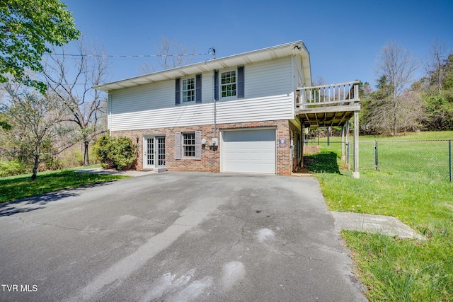 traditional home featuring a front yard, a garage, fence, brick siding, and driveway