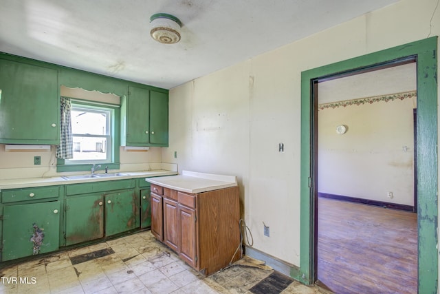 kitchen with light countertops, green cabinets, a sink, and baseboards