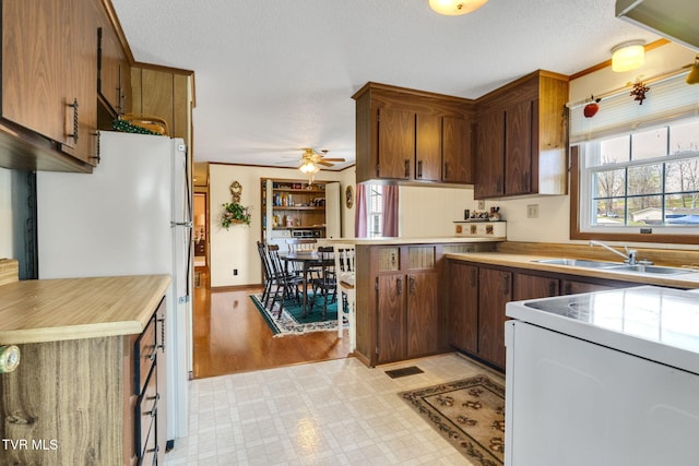 kitchen with light floors, white appliances, light countertops, ceiling fan, and a sink