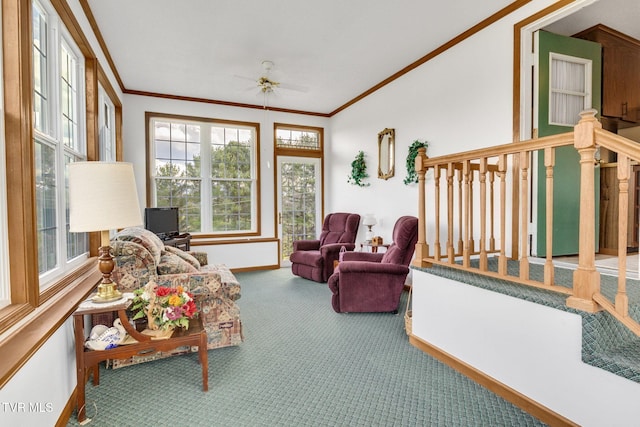 carpeted living room featuring stairway, baseboards, crown molding, and ceiling fan