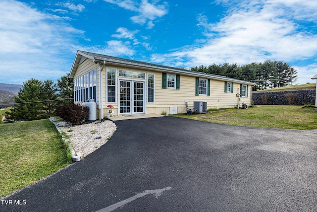 view of front of house with a front lawn, cooling unit, and aphalt driveway