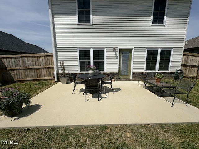 rear view of house with a fenced backyard and a patio