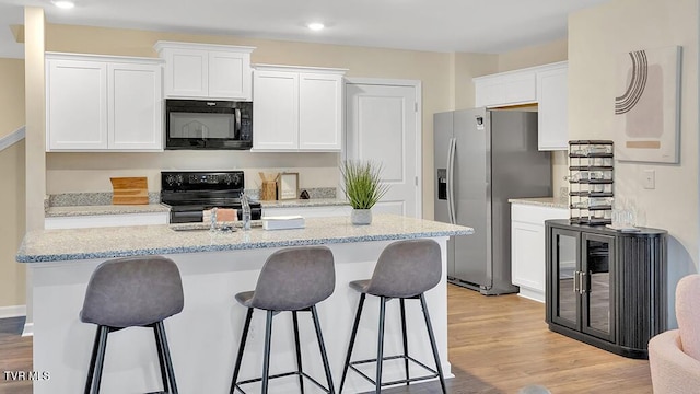 1128 Aspen Ter, Greeneville, TN 37745 - kitchen featuring black appliances, white cabinets, a kitchen island with sink, a kitchen bar, and recessed lighting