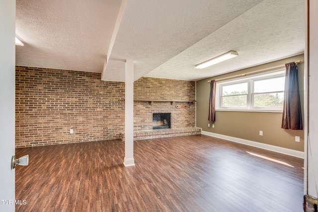 132 Lancaster Dr, Kingsport, TN 37663 - unfurnished living room with brick wall, a fireplace, dark wood finished floors, and a textured ceiling